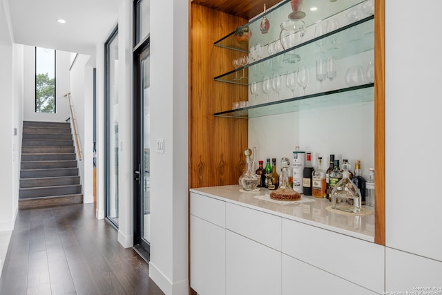 bar with dark hardwood / wood-style floors and white cabinetry