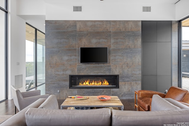 living room featuring a healthy amount of sunlight, a tiled fireplace, and hardwood / wood-style floors