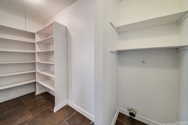 interior space with a textured ceiling, dark tile floors, and electric dryer hookup