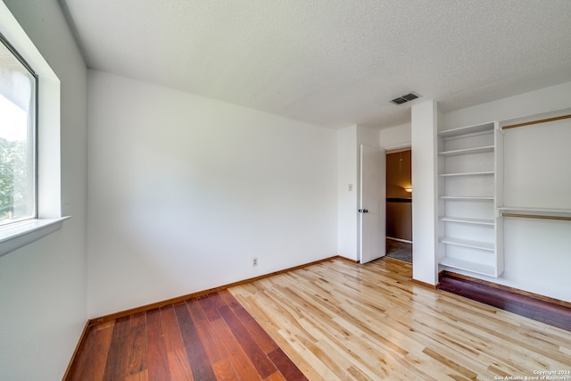 unfurnished bedroom with a textured ceiling and light hardwood / wood-style floors