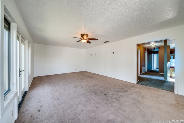 carpeted empty room featuring a healthy amount of sunlight, ceiling fan, and a textured ceiling