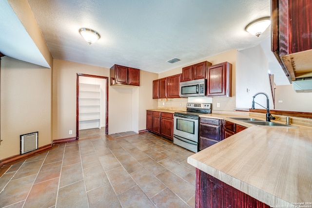 kitchen with appliances with stainless steel finishes, sink, kitchen peninsula, and light tile floors