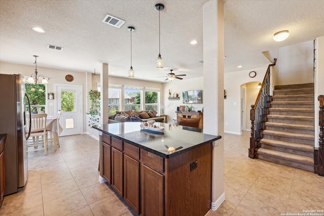 kitchen with ceiling fan with notable chandelier, pendant lighting, light tile floors, and stainless steel fridge