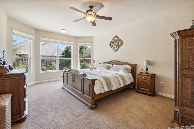 bedroom with light colored carpet, a textured ceiling, and ceiling fan