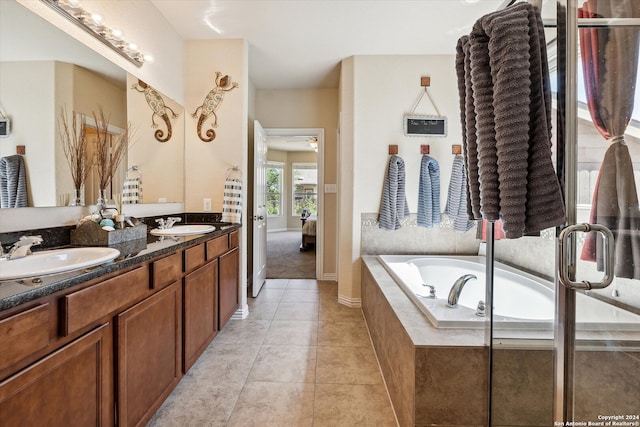 bathroom featuring tile flooring, tiled tub, and dual vanity