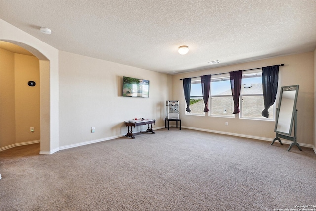 unfurnished room featuring light colored carpet and a textured ceiling