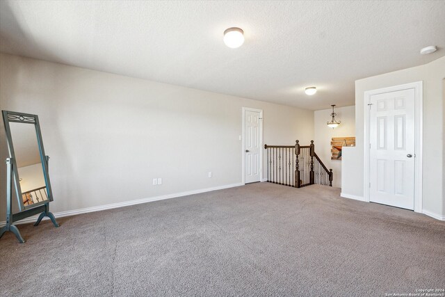 interior space featuring a textured ceiling and dark colored carpet