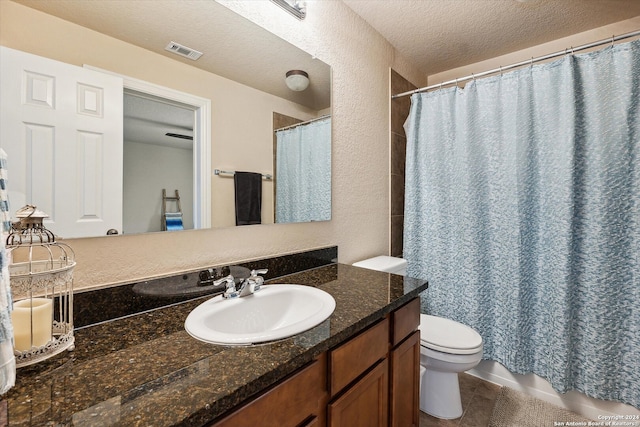 bathroom with vanity with extensive cabinet space, toilet, tile flooring, and a textured ceiling