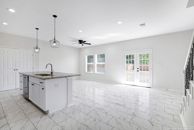 kitchen with stone countertops, ceiling fan, sink, light tile flooring, and a center island with sink