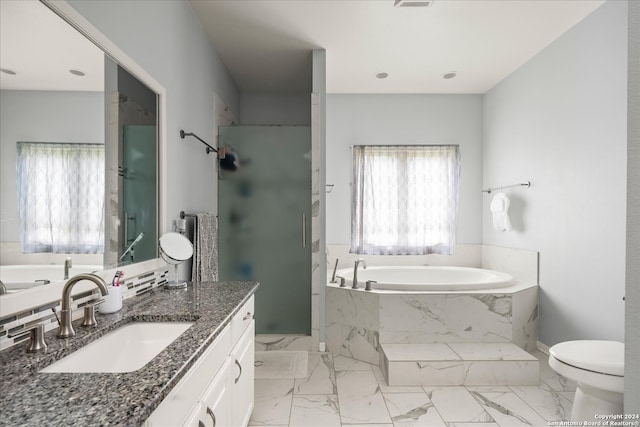 bathroom with tile floors, tiled tub, vanity, and toilet