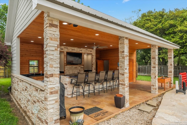 view of patio featuring ceiling fan and a bar