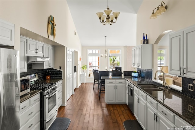 kitchen with decorative light fixtures, appliances with stainless steel finishes, wall chimney range hood, and tasteful backsplash