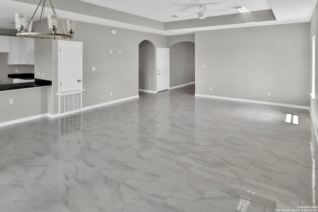 tiled empty room with ceiling fan and a raised ceiling