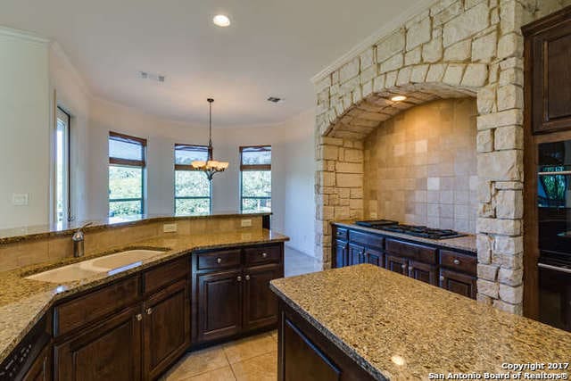 kitchen with backsplash, light tile patterned floors, a notable chandelier, sink, and gas cooktop