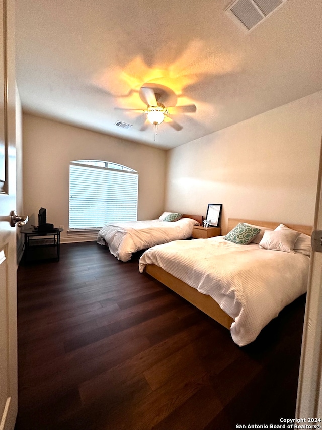 bedroom featuring ceiling fan, dark hardwood / wood-style floors, and a textured ceiling