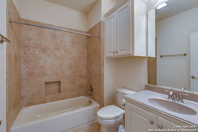 full bathroom featuring tiled shower / bath, vanity, and toilet