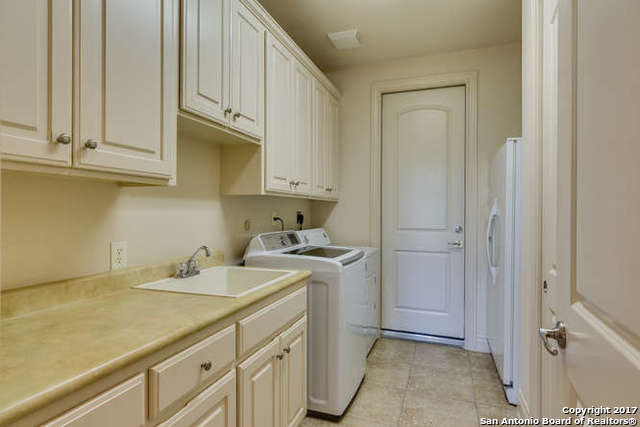 laundry area featuring cabinets, separate washer and dryer, light tile patterned floors, and sink