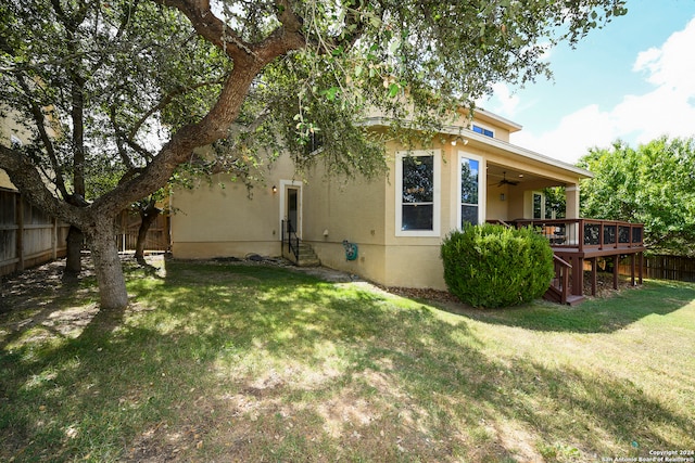 rear view of property featuring a wooden deck, a lawn, and ceiling fan