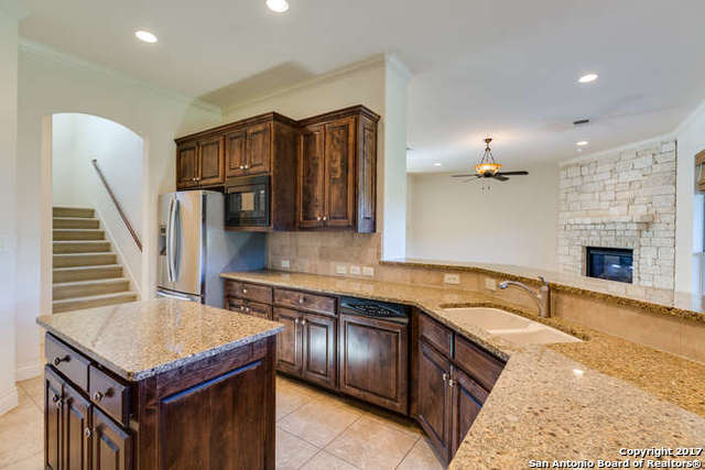 kitchen featuring a fireplace, sink, decorative backsplash, ceiling fan, and black microwave