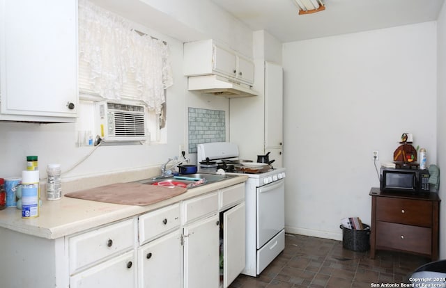 kitchen with white cabinets, sink, dark tile floors, and white gas stove