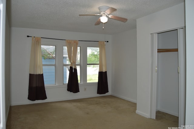 unfurnished bedroom featuring light carpet, a closet, ceiling fan, and a textured ceiling