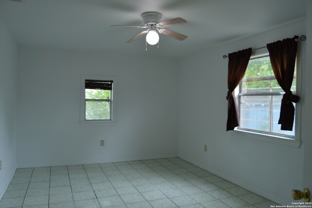 tiled empty room featuring ceiling fan