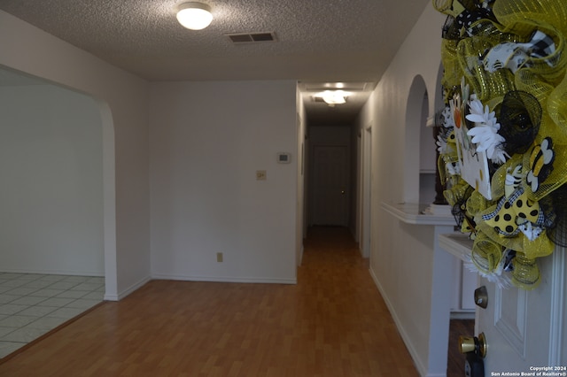 hallway with a textured ceiling and light tile flooring