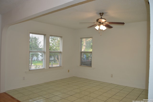 spare room featuring a healthy amount of sunlight, ceiling fan, and light tile flooring