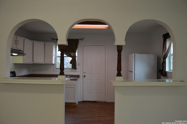 kitchen with white cabinets, white fridge, and dark wood-type flooring