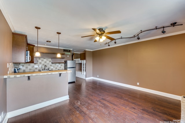 kitchen featuring ornamental molding, dark hardwood / wood-style flooring, stainless steel appliances, and hanging light fixtures