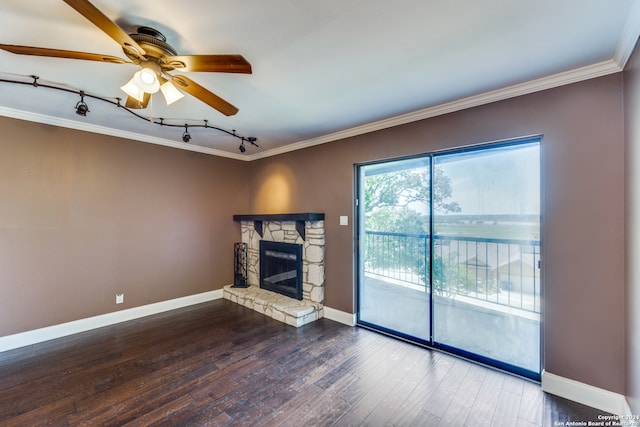 unfurnished living room with crown molding, dark hardwood / wood-style flooring, a stone fireplace, ceiling fan, and track lighting