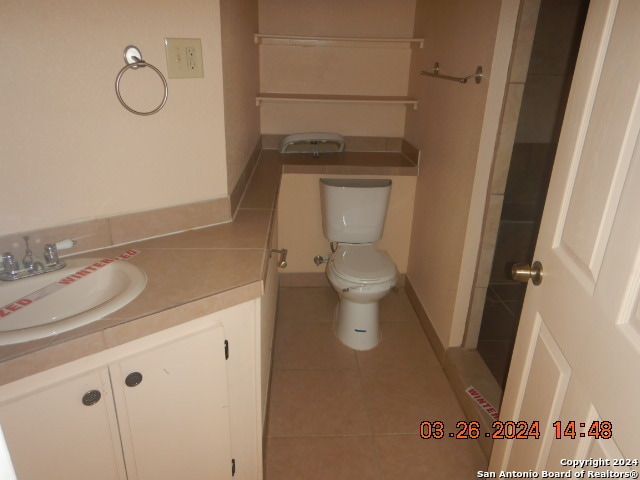 bathroom featuring toilet, tile flooring, and vanity