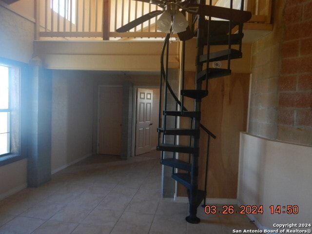 staircase featuring ceiling fan and light tile floors