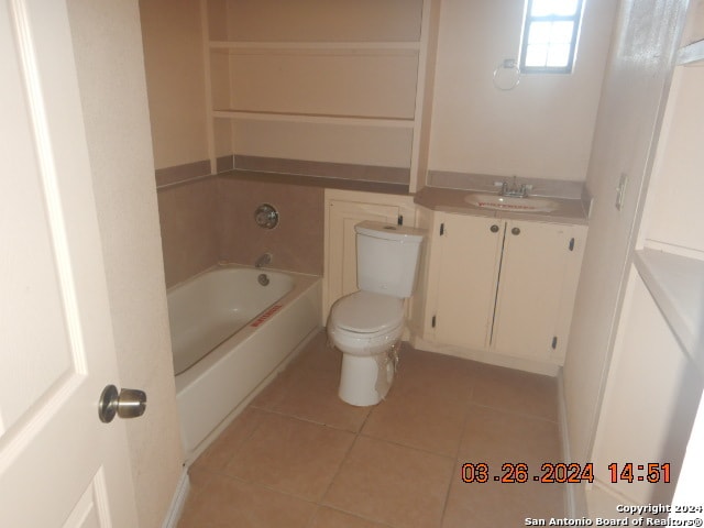 bathroom featuring tile floors, vanity, a tub, and toilet