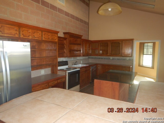 kitchen with stainless steel appliances, tile flooring, sink, a kitchen island, and tasteful backsplash