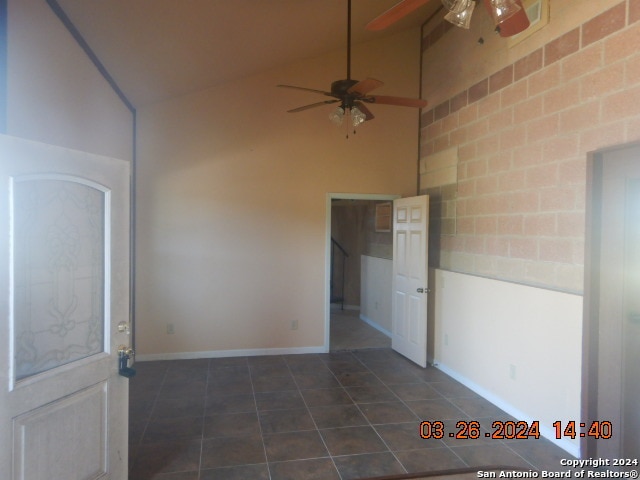 tiled empty room featuring high vaulted ceiling and ceiling fan