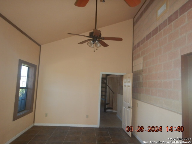 empty room with high vaulted ceiling, ceiling fan, and dark tile floors