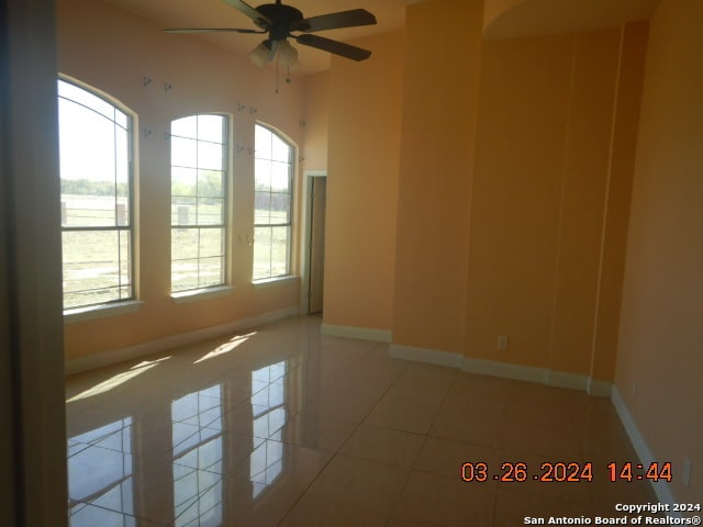 spare room featuring ceiling fan, light tile floors, and a wealth of natural light