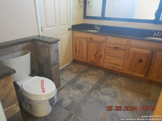 bathroom featuring toilet, tile floors, and dual vanity