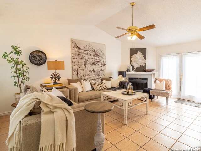 tiled living room featuring vaulted ceiling, ceiling fan, and a tiled fireplace