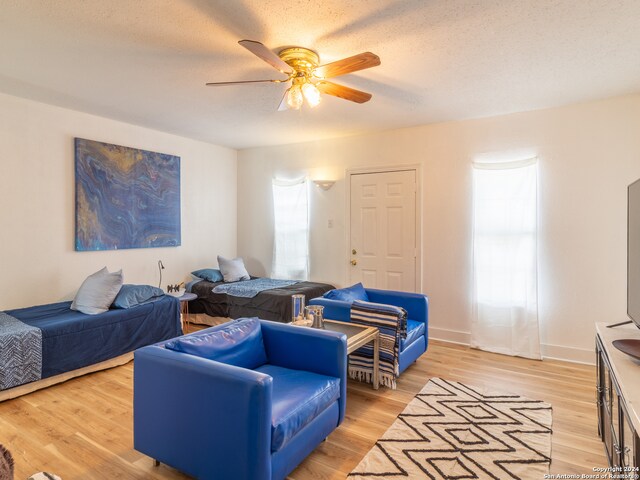 bedroom with light hardwood / wood-style flooring, ceiling fan, and a textured ceiling