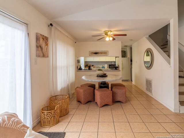 tiled dining space with vaulted ceiling and ceiling fan