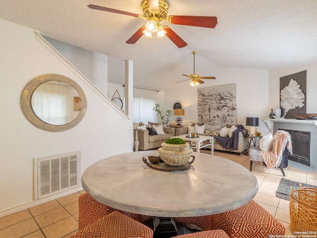 dining room featuring a textured ceiling, ceiling fan, light tile floors, and lofted ceiling