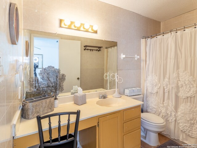 bathroom featuring tile walls, vanity, and toilet