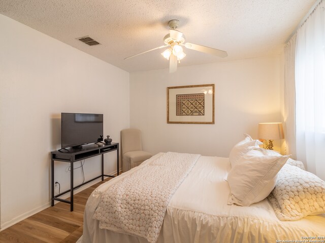 bedroom featuring ceiling fan, light wood-type flooring, and a textured ceiling