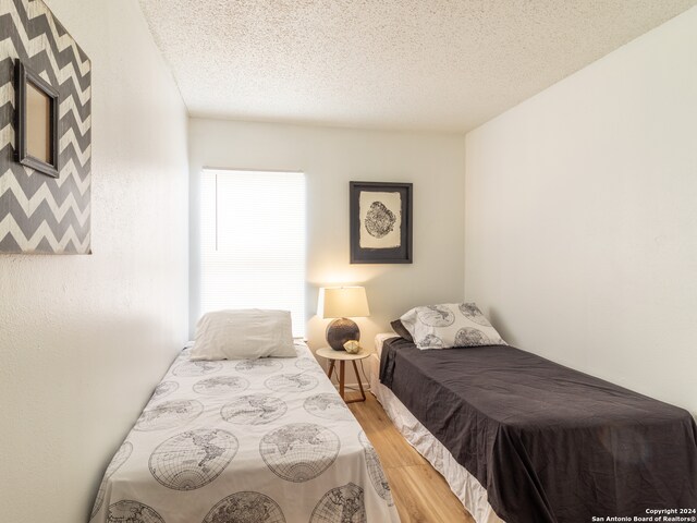 bedroom featuring light hardwood / wood-style floors and a textured ceiling