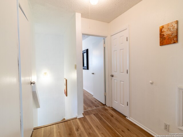 hallway with a textured ceiling and light wood-type flooring