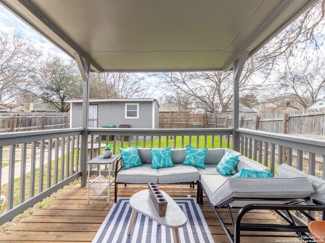 wooden deck with outdoor lounge area, a yard, and a storage unit