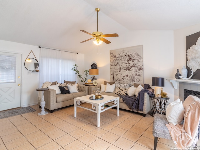 living room with ceiling fan, lofted ceiling, a healthy amount of sunlight, a fireplace, and light tile floors