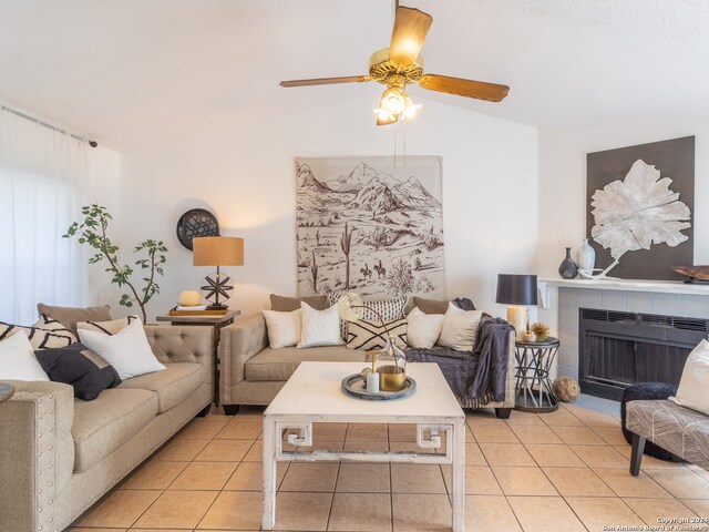 living room featuring a tiled fireplace, ceiling fan, and light tile flooring